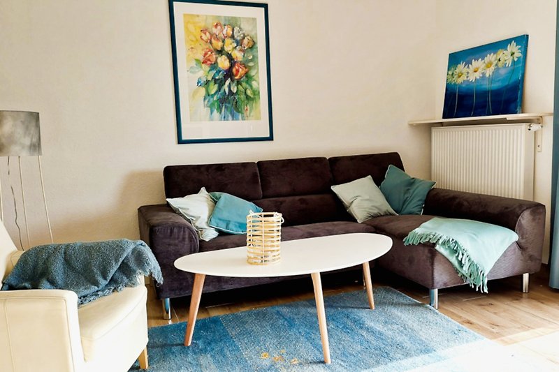 Gemütliches Wohnzimmer mit blauer Couch und gelben Kissen.