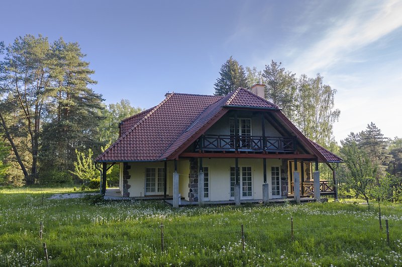 Rustikales Haus mit Garten, Bäumen und weitem Feld.