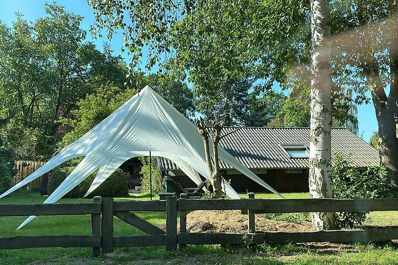 Ein idyllischer Ort zum Entspannen unter einem schattigen Baum und einem Zelt.