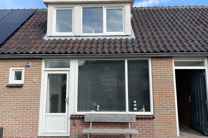 Voorkant met deur en bankje en poortdeur voor achterom.