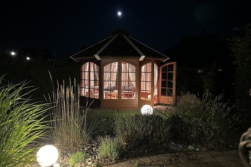 Gemütliches Haus mit schönem Garten und malerischer Landschaft unter dem Mondschein.