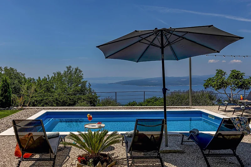 Poolterrasse mit Liegen und Sonnenschirmen für entspannte Tage.