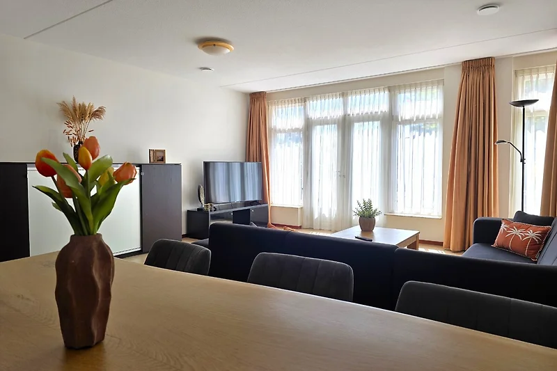 Großzügiger Wohnbereich mit Sofa, Holzdecke, Pflanzen und viel Licht.