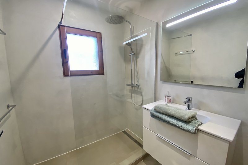 Een moderne badkamer met een spiegel, douche en kraan.