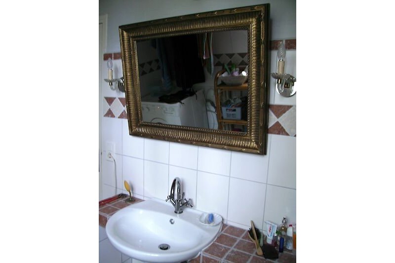 Gemütliches Badezimmer mit Spiegel, Waschbecken und Marmor- Fliesen.