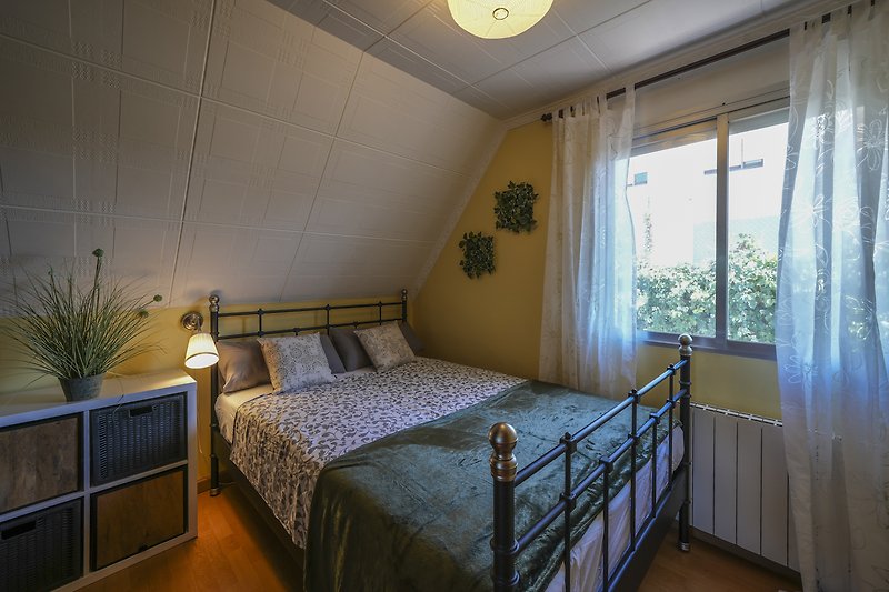 Gemütliches Schlafzimmer mit stilvollem Mobiliar und Fensterbehang.