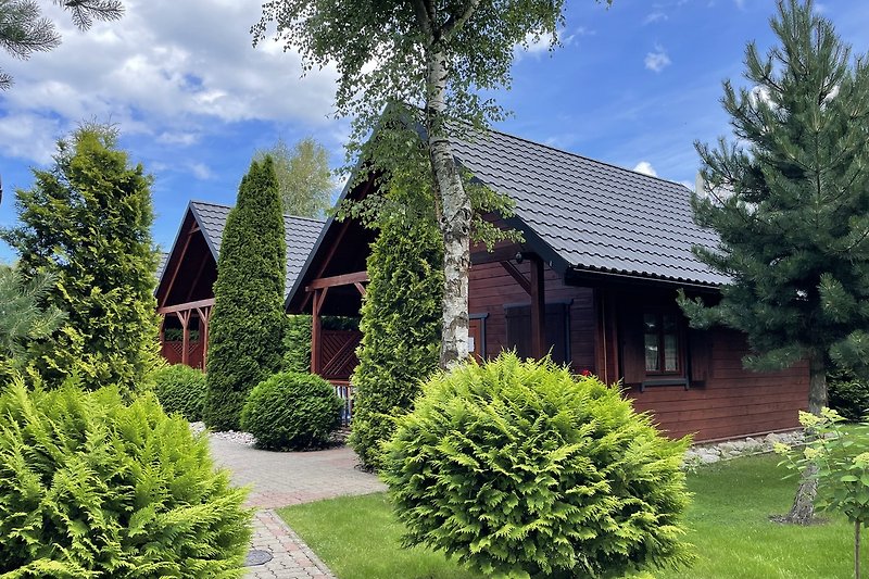 Gemütliches Landhaus mit Garten, Bäumen und blühenden Sträuchern.