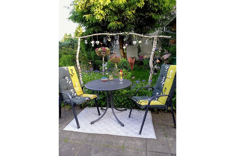 Schöner Garten mit Blumen, Pflanzen und gemütlicher Außenmöbel. Perfekt zum Entspannen im Freien.