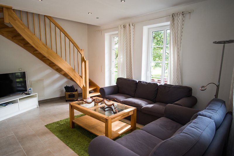 Gemütliches Wohnzimmer Fewo I mit bequemer Couch, stilvollem Möbel und schöner Holzverkleidung.