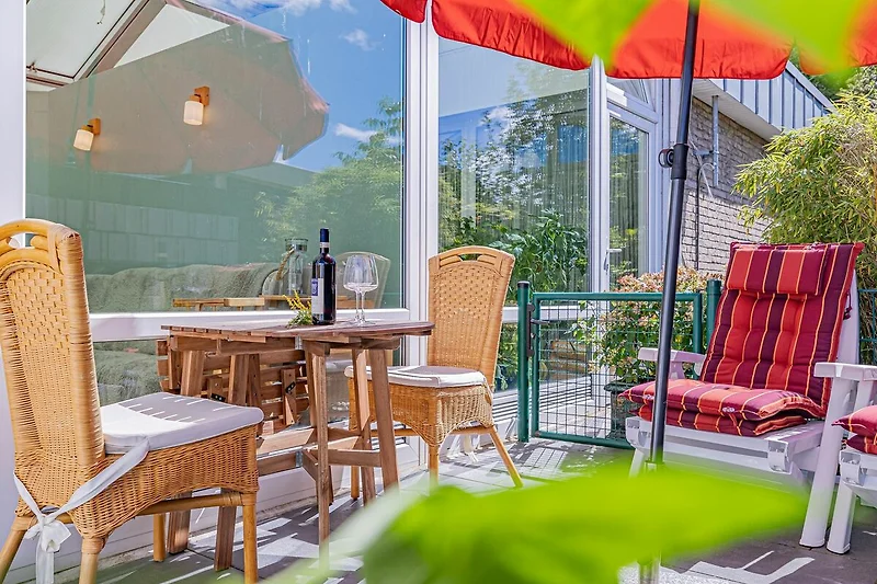 Sonnige Terrasse mit Gartenmöbeln und Sonnenliegen