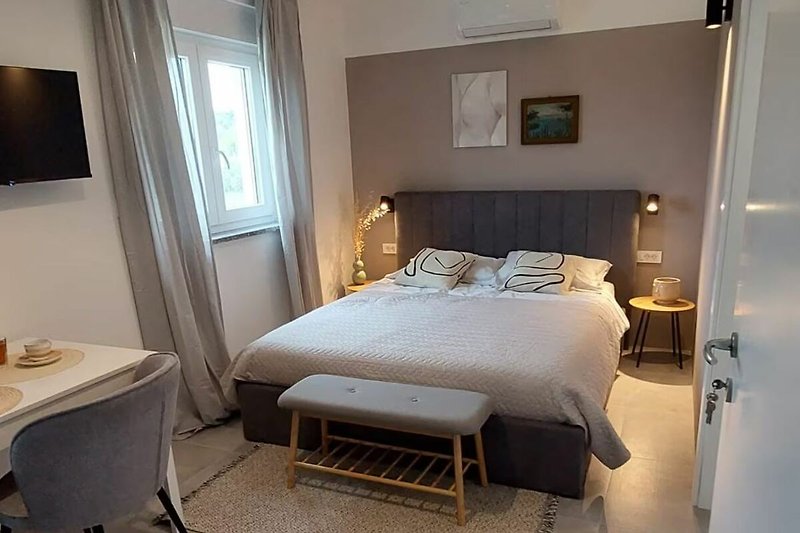 Modernes Schlafzimmer mit Holzbett und Vorhängen.