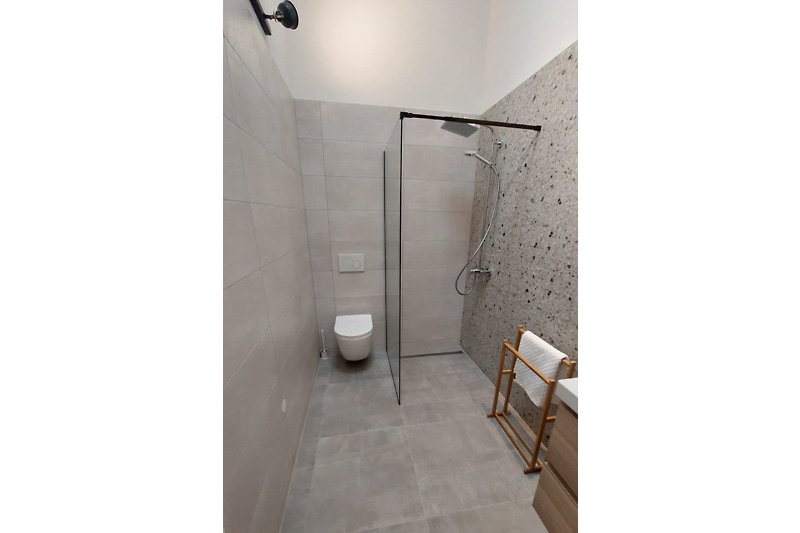 Moderne Badezimmerausstattung mit Glasdusche und Metallarmaturen.