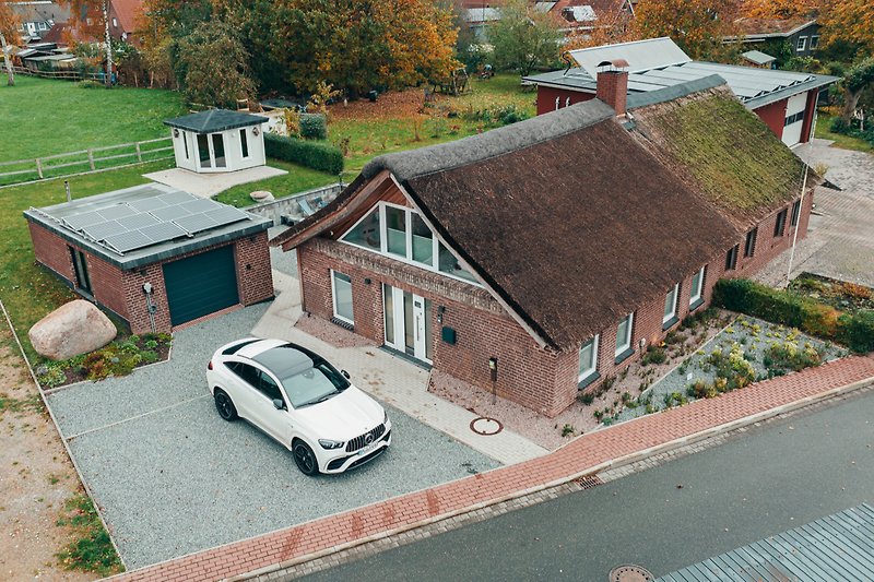 Schönes Haus mit gepflasterter Auffahrt, grüner Landschaft und Parkplatz.