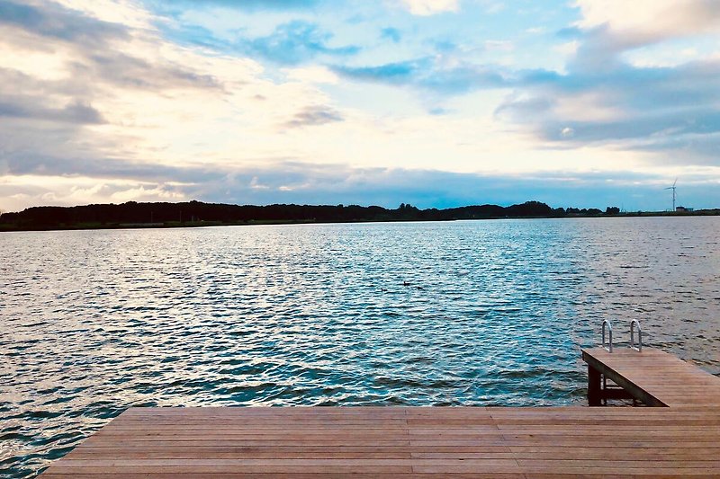 Ruhiger See mit Holzsteg und malerischem Sonnenuntergang