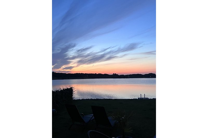 Genießen Sie den atemberaubenden Sonnenuntergang am ruhigen Seeufer mit bequemen Outdoor-Möbeln