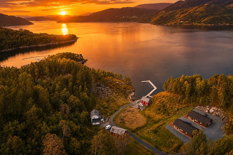 Sonnenuntergang am See mit Inseln, Bergen und spiegelndem Wasser.