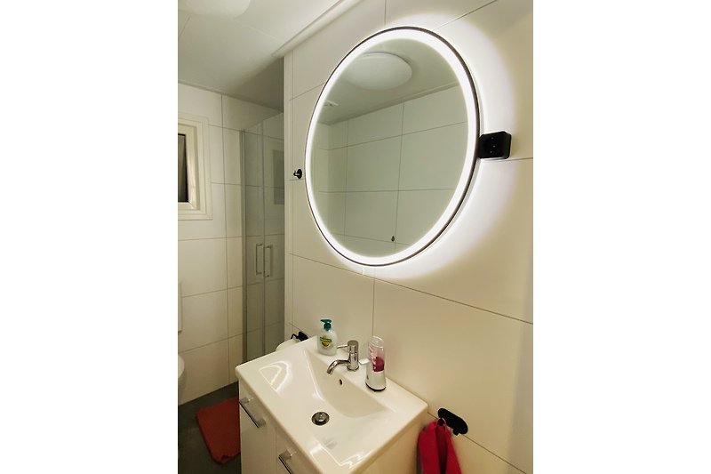 Spiegel, Waschbecken, und Armaturen im Badezimmer.