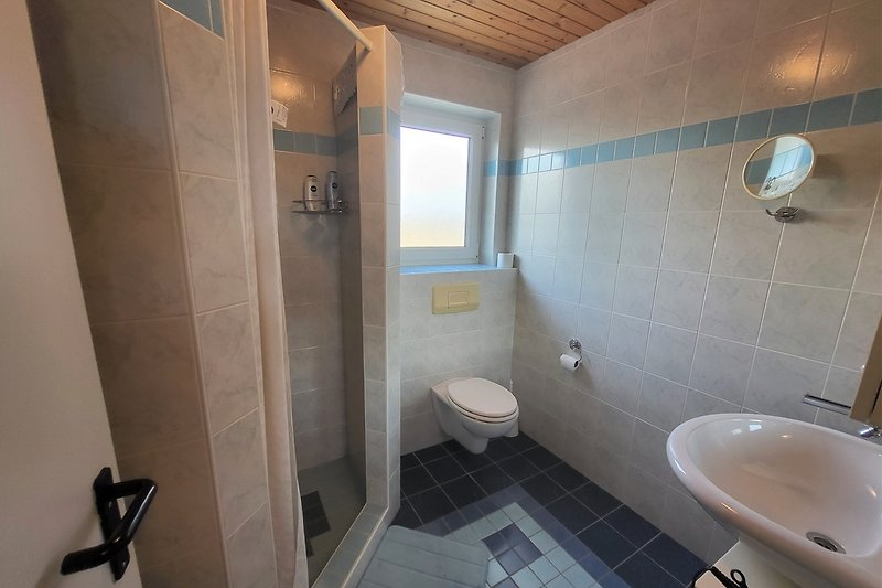 Badezimmer mit Spiegel, Waschbecken und Toilette.