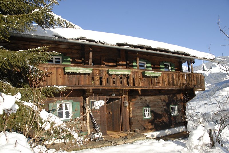 Winterliches Ferienhaus mit verschneitem Dach und malerischer Bergkulisse.