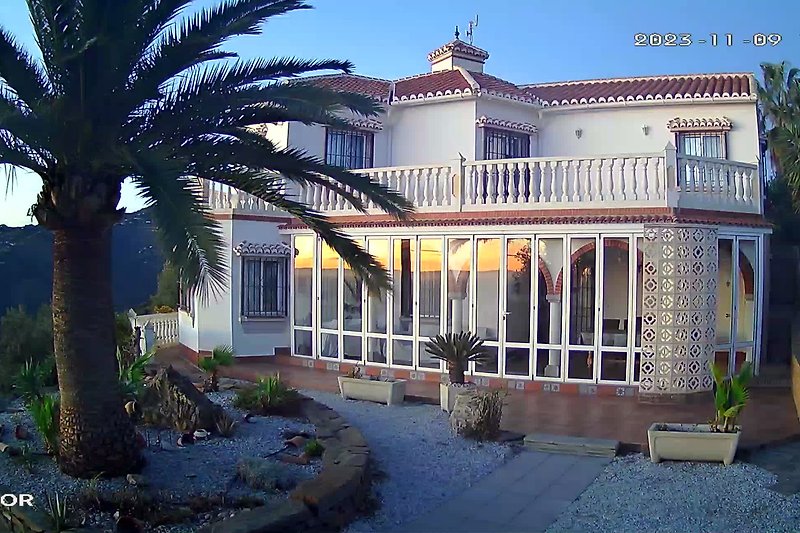 Schönes Haus mit großem Fenster, Palmen und blauem Himmel. Perfekt für einen erholsamen Urlaub!
