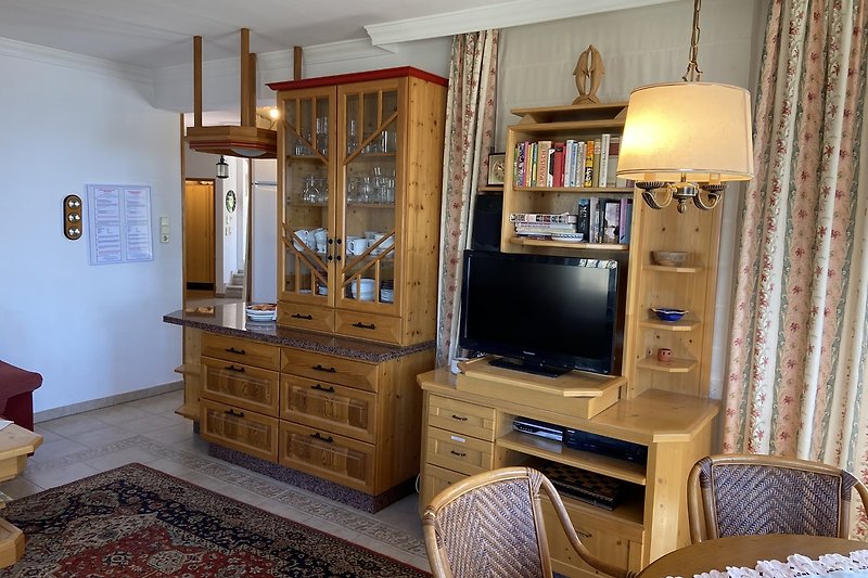 Gemütliches Wohnzimmer mit Holzmöbeln, Fernseher und stilvoller Einrichtung.