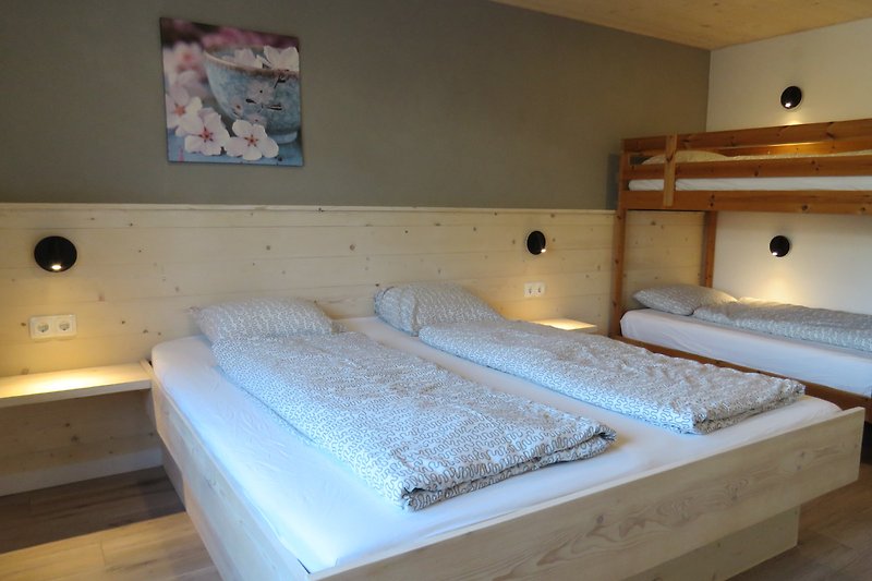 Gemütliches Schlafzimmer mit bequemem Bett, Holzmöbeln und gemütlicher Beleuchtung. 4 Personen