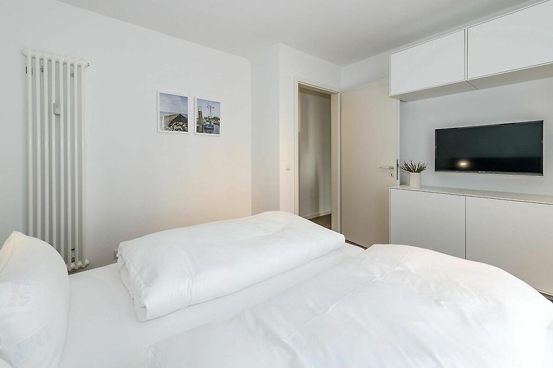 Schlafzimmer mit Doppelbett. Kleiderschrank und Flatscreen TV