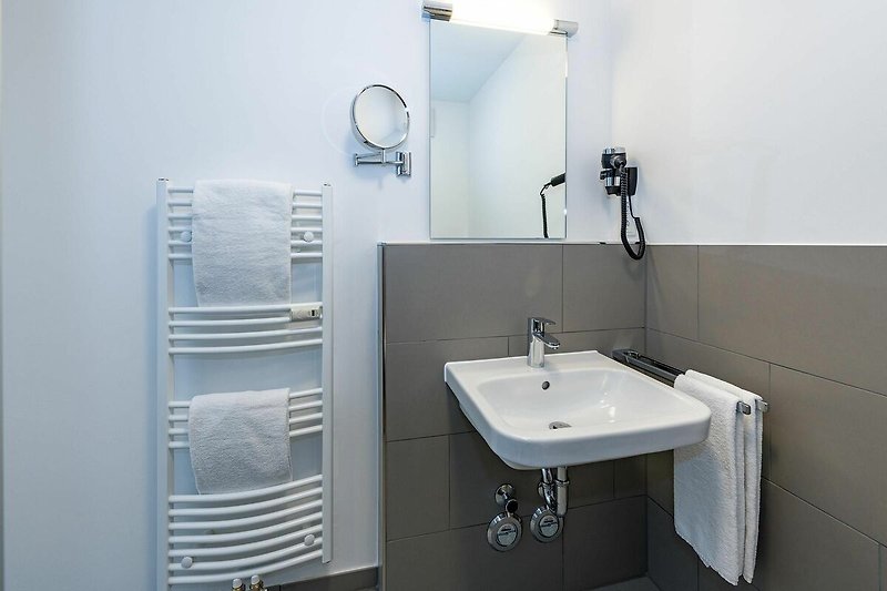 Badezimmer mit Dusche, Waschtisch und Spiegel