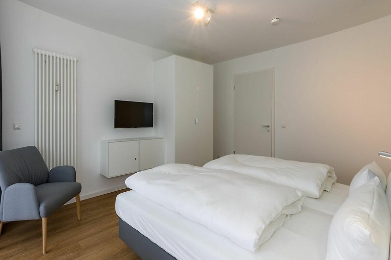 Schlafzimmer mit Doppelbett, Kleiderschrank und Flatscreen-TV