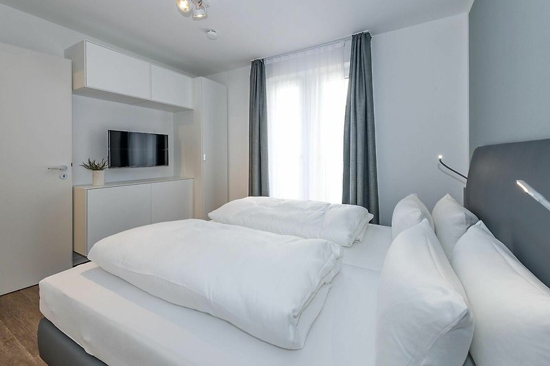 Schlafzimmer mit Doppelbett, Kleiderschrank und Flatscreen-TV