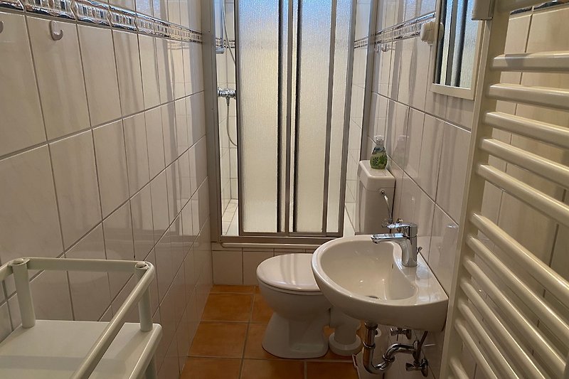 Duschbad mit Handtuchheizkörper, Fenster und Ventilator.