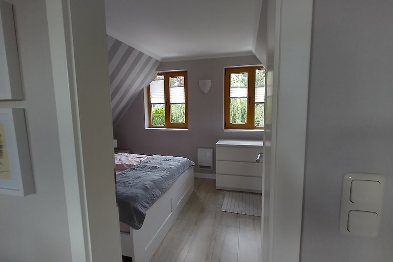 Gemütliches Schlafzimmer mit stilvollem Interieur, Holzbett und Fensterbehang.