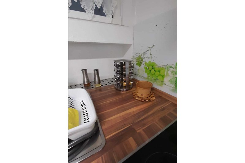 Küche mit Holzakzenten, Geschirr und Pflanze.