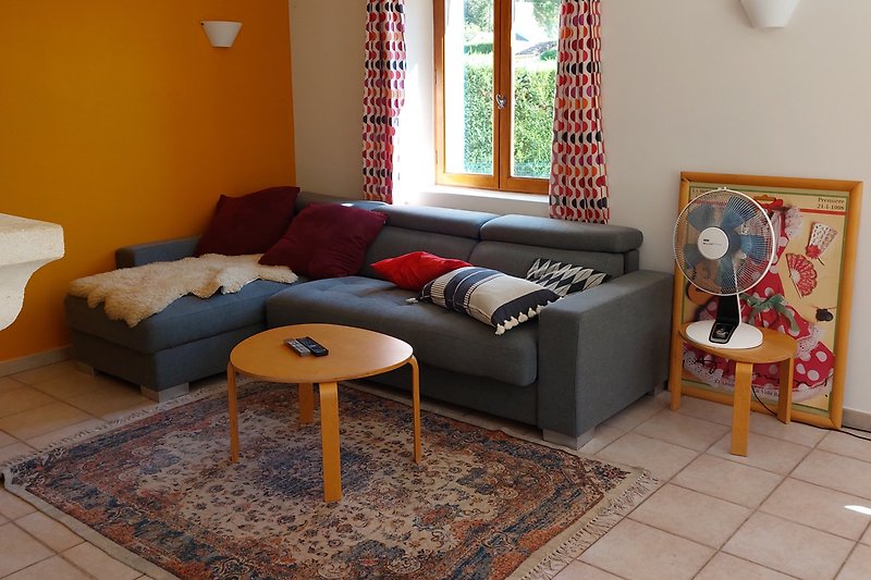 Gemütliches Wohnzimmer mit Holzmöbeln, Couch und Fenster.