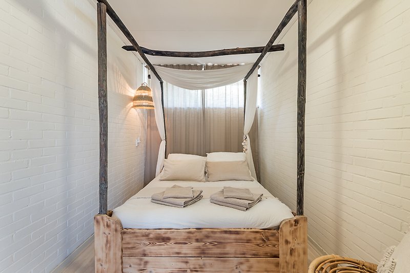 Comfortabel bed met houten hemel en stijlvolle inrichting.