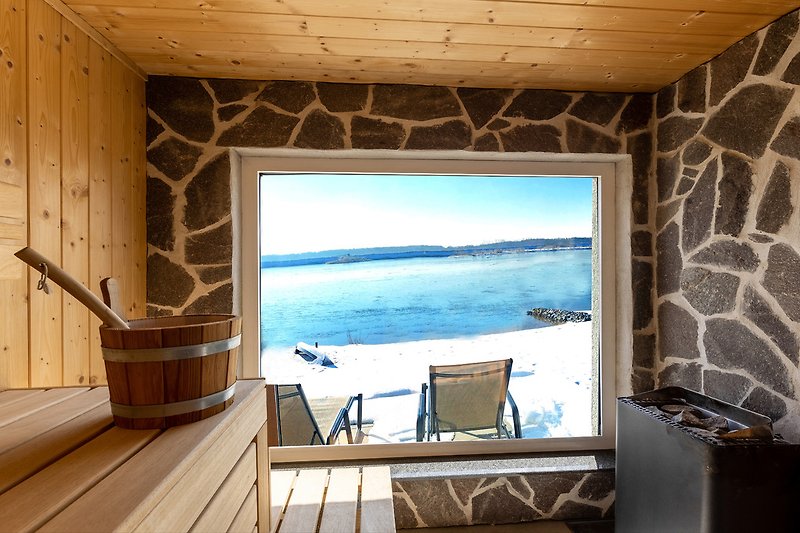 Blick aus der Sauna direkt auf den verschneiten Strand, danach können Sie auf den komfortablen Liegen relaxen.