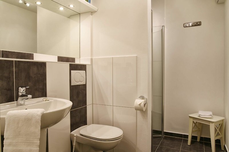 Auch das Badezimmer mit bodengleicher Dusche ist modern und hell gehalten.