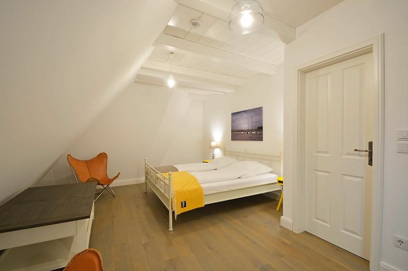 Ein Blick in ein weiteres Schlafzimmer im Obergeschoss, welches ebenfalls mit einem Doppelbett ausgestattet ist.