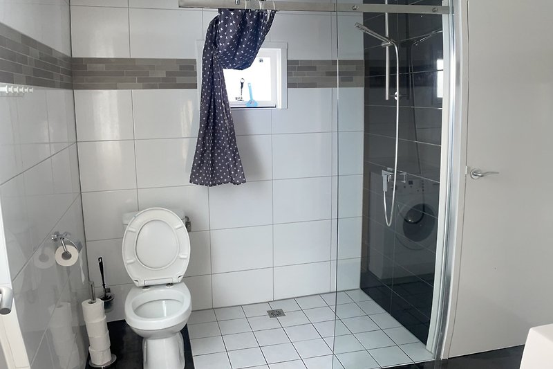 Ruime badkamer met glazen douchewand en toilet
