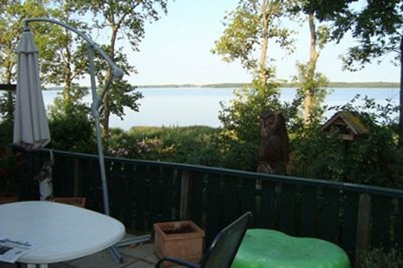Aussicht von der 28 m² grossen Terrasse mit Gartenmöbeln auf den See.