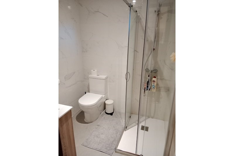 Modernes Badezimmer mit Toilette, Dusche und Fenster.