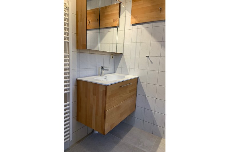 Schönes Badezimmer mit Holzboden, Fliesen und Glasdusche.