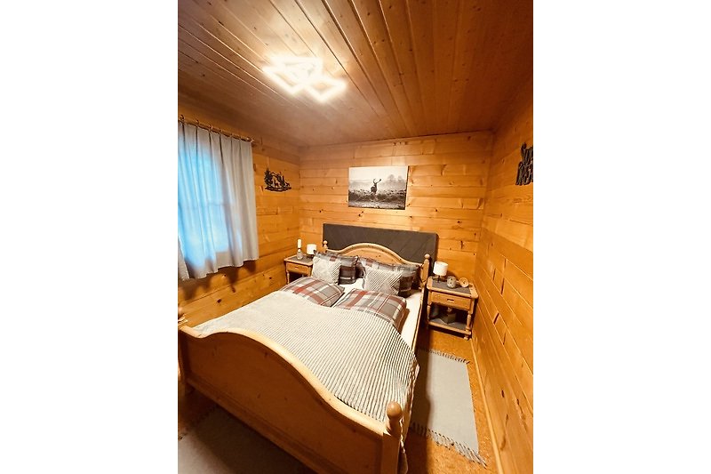 Holzinterieur mit bequemem Bett, stilvoller Lampe und Vorhang.