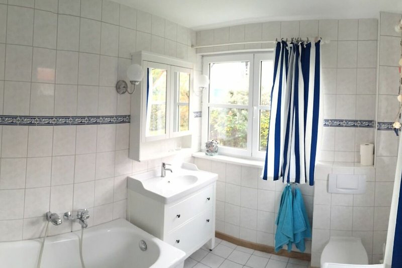 Badezimmer mit Spiegel, Waschbecken, WC und Badewanne