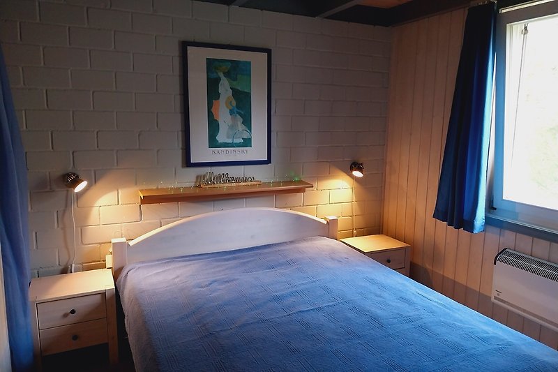 Gemütliches Schlafzimmer mit Holzmöbeln und gemütlichem Bett im EG