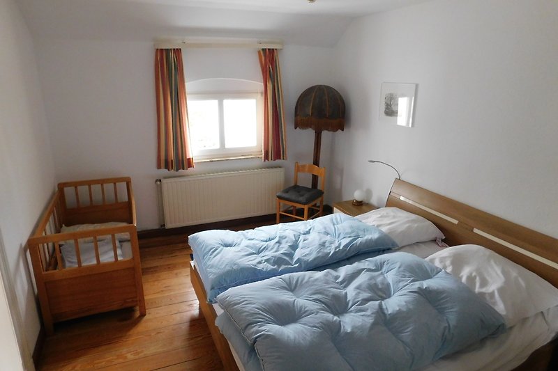Schlafzimmer mit Holzmöbeln, Bett, Lampe und Fenster. Schlafzimmer unten