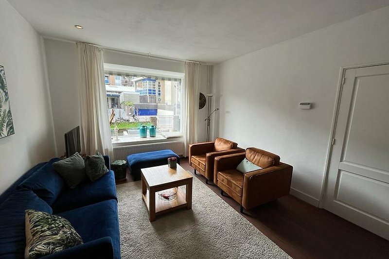 Gemütliches Wohnzimmer mit bequemer Couch, stilvollem Interieur und Holzmöbeln.