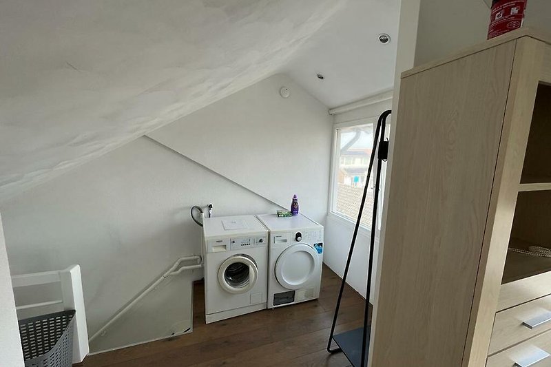 Gemütlicher Waschraum mit Holzboden, Waschmaschine und Wäschetrockner.