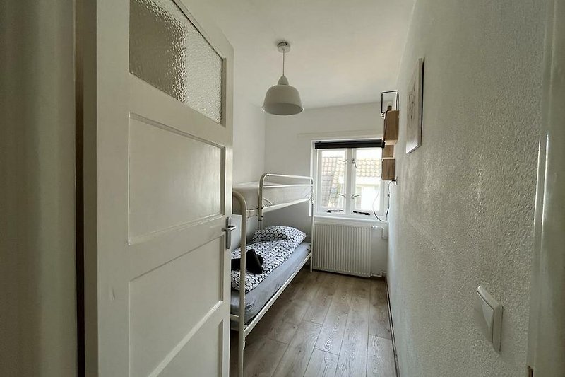 Gemütliches Apartment mit Holzboden, bequemem Bett und stilvoller Beleuchtung.