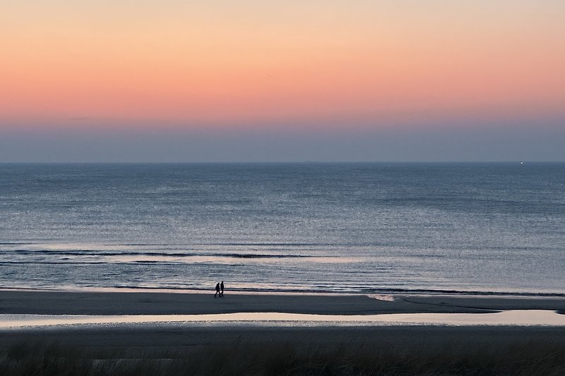 Ruhige Küstenlandschaft mit Strand, Meer und Sonnenuntergang.